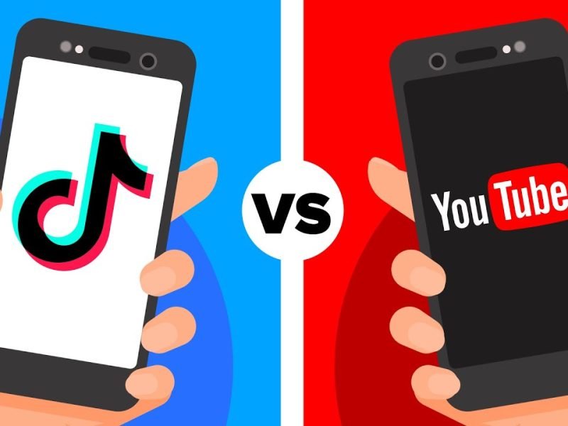 image showing two hands holding 2 phones. one phone has the tiktok logo and the other has youtube logo with VS sign in the middle.